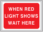 When red light shows wait here roll up road sign