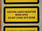Caution laser radiation when open do not stare into beam, laser equipment warning safety label.