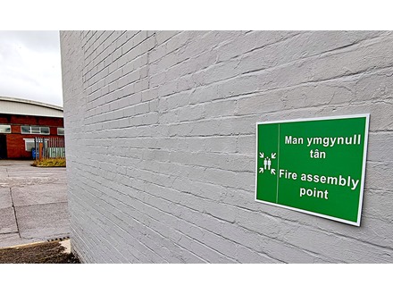 Man ymgynull tân / Fire assembly point. Welsh English sign