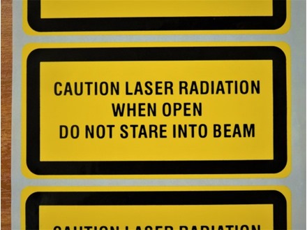 Caution laser radiation when open do not stare into beam, laser equipment warning safety label.